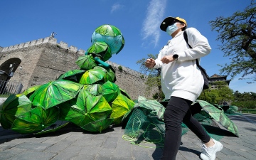 الصورة: الصورة: فنانة صينية تظهر في "يوم الأرض" بزي غريب للفت الانتباه إلى قضايا المناخ والبيئة.. فيديو