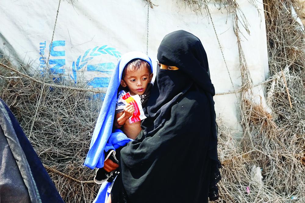الصورة : A Yemeni woman displaced by conflict holds her son of two years and eight months, weighing only five kilograms, as she waits outside a shelter for the displaced in the war-ravaged western Hodeida province, on February 15, 2021. (Photo by Khaled Ziad / AFP)