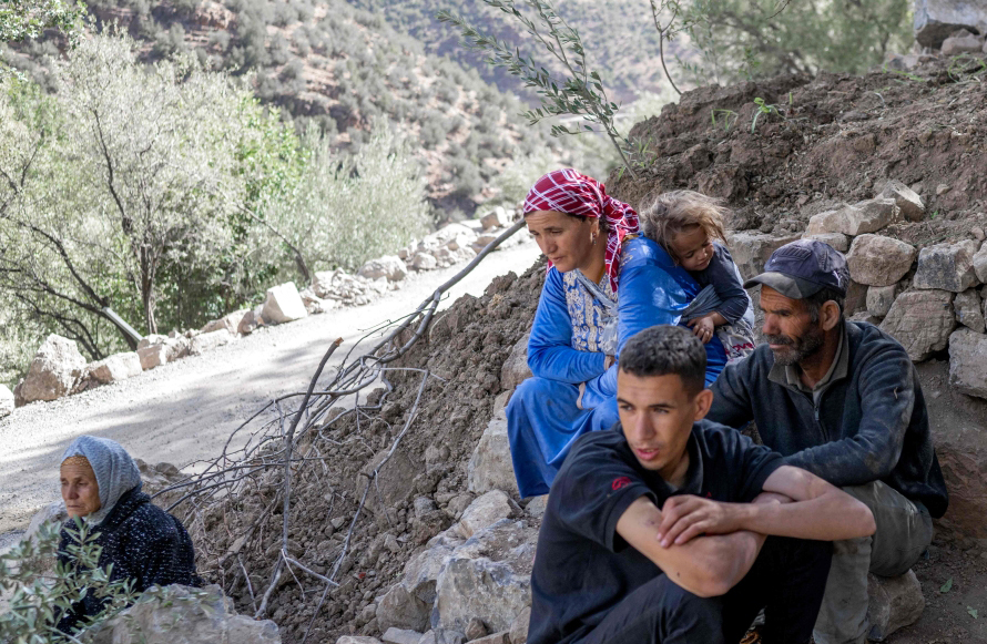 الصورة : مغاربة يجلسون بجانب منزلهم في قرية تيغيشت المتضررة جراء الزلزال | أ ف ب